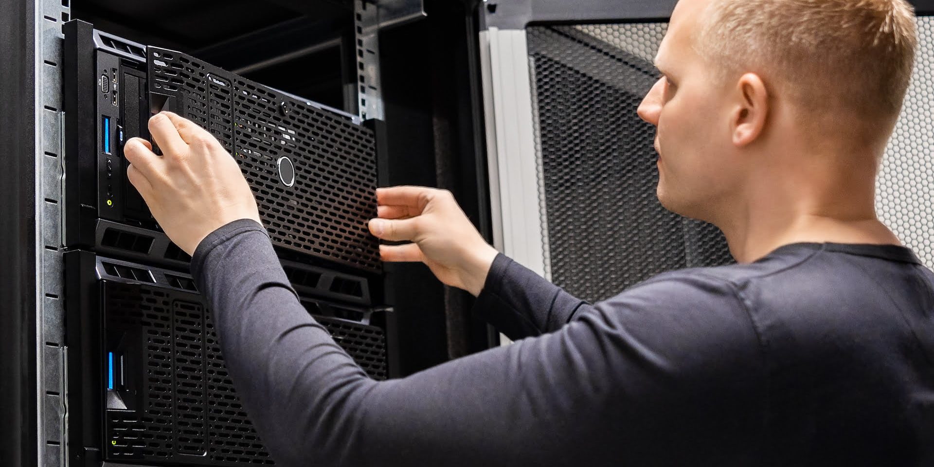 Confident male technician installing servers in enterprise datacenter for cloud hosting.